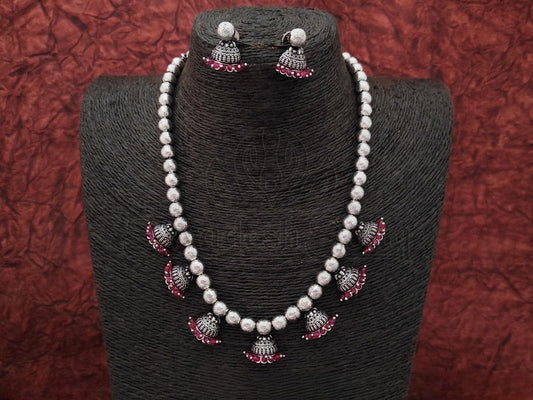 Make a bold & dazzling statement with Oxidized Silver Necklace & Jhumka Set w/ Ruby Embellishments from swadeshsouq.com.